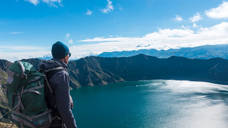 A man looks down on a mountain lake from above