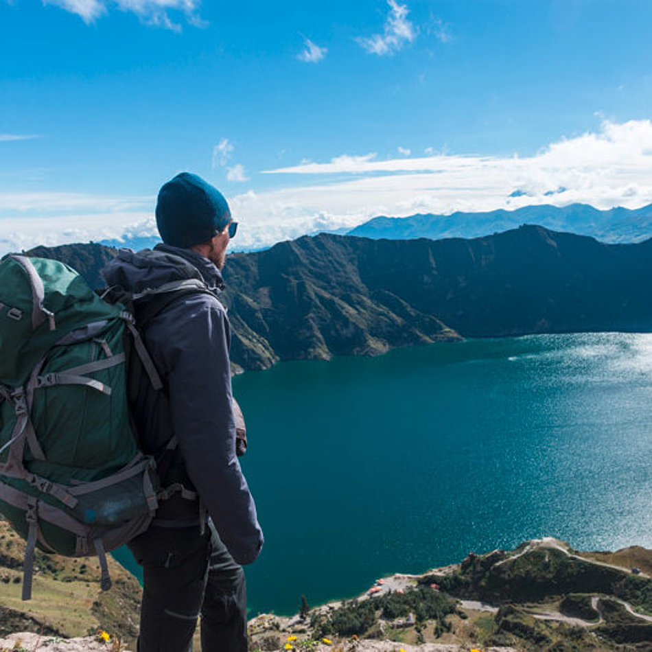 A man looks down on a mountain lake from above