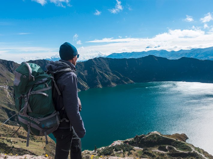 A man looks down on a mountain lake from above