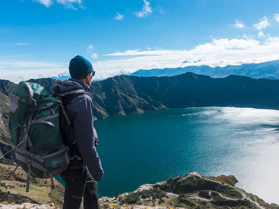 A man looks down on a mountain lake from above