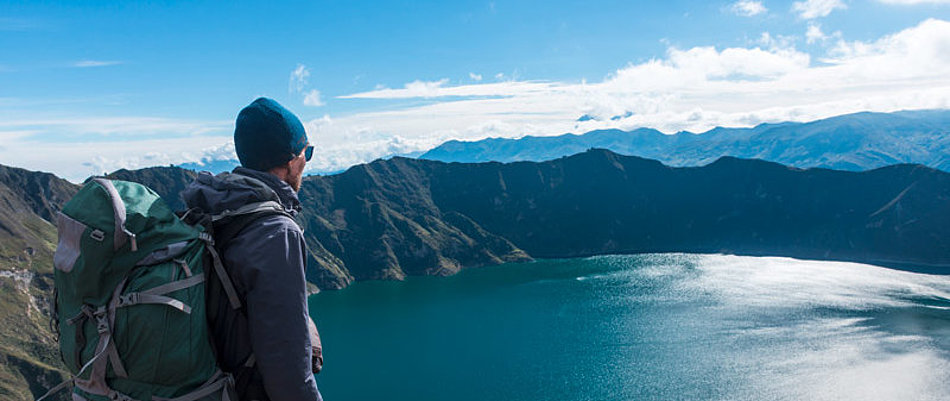 A man looks down on a mountain lake from above