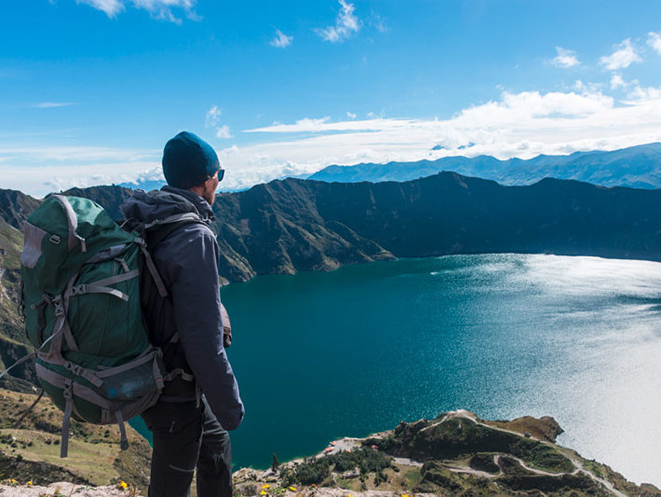 A man looks down on a mountain lake from above