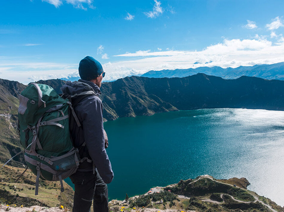 Sustainable hiking tourism A man looks down on a mountain lake from above