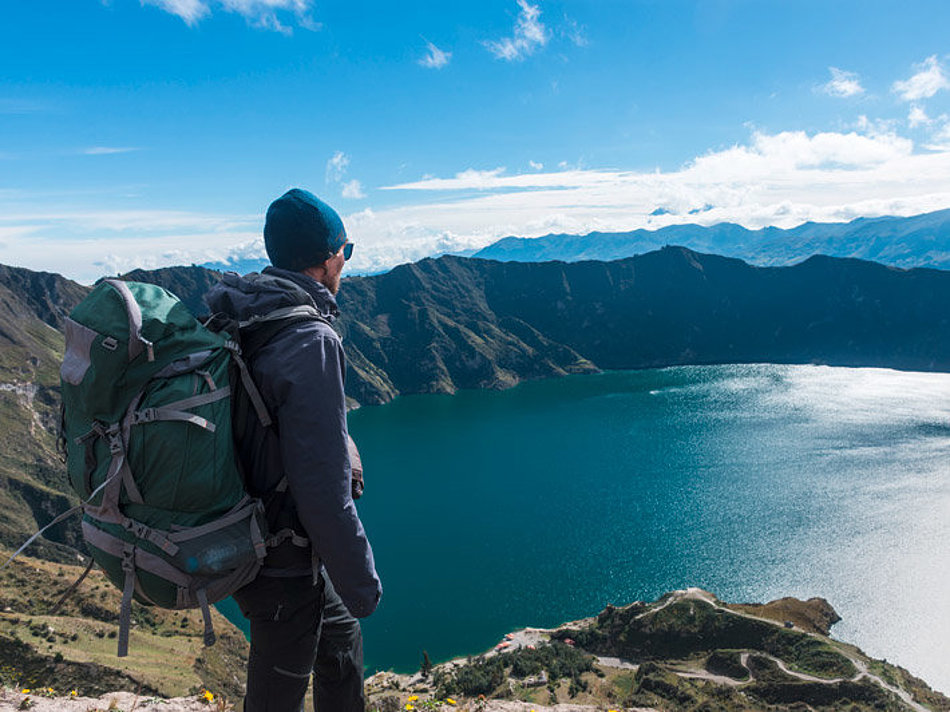 A man looks down on a mountain lake from above