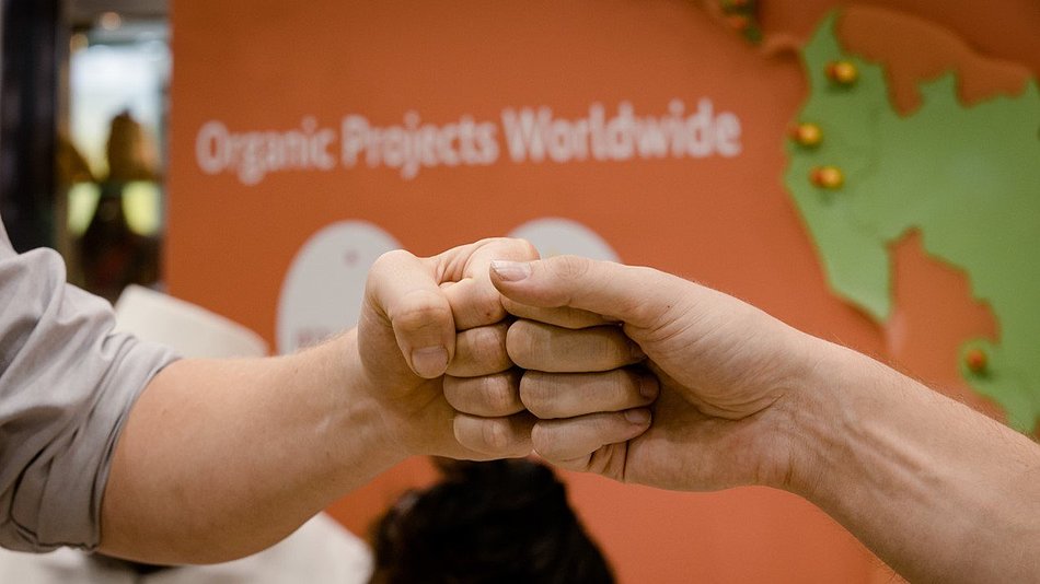 Two people greet each other via fist bump