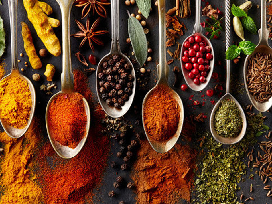 A selection of different spices is presented on spoons