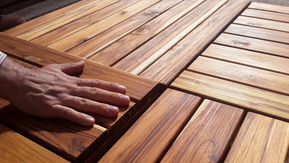 A hand is feeling wooden boards